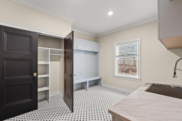 interior space with crown molding, a sink, and baseboards