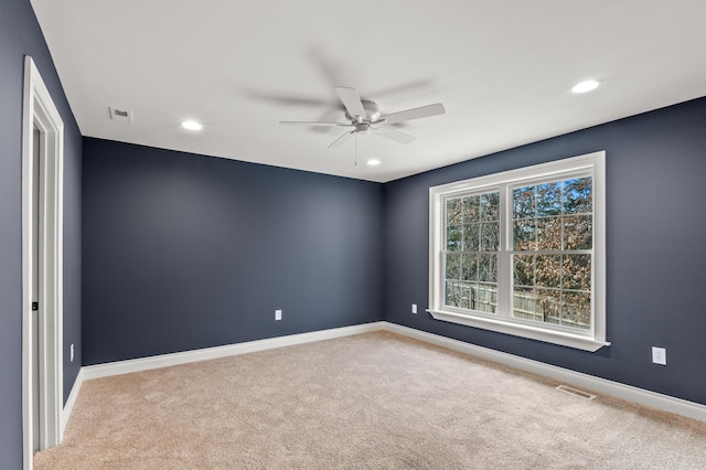 carpeted empty room with ceiling fan, visible vents, and baseboards