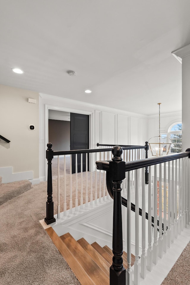 stairway featuring recessed lighting, a decorative wall, carpet, and an inviting chandelier