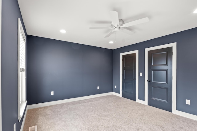 unfurnished bedroom with carpet floors, a ceiling fan, visible vents, and baseboards