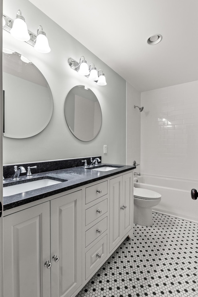 bathroom with double vanity, bathtub / shower combination, a sink, and toilet