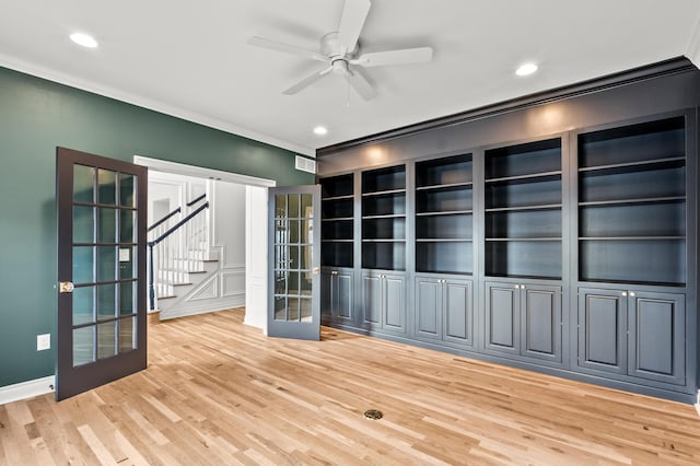 spare room with a ceiling fan, light wood-style floors, stairs, french doors, and ornamental molding