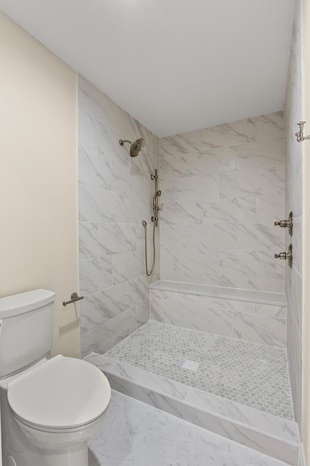 full bathroom featuring marble finish floor, tiled shower, and toilet