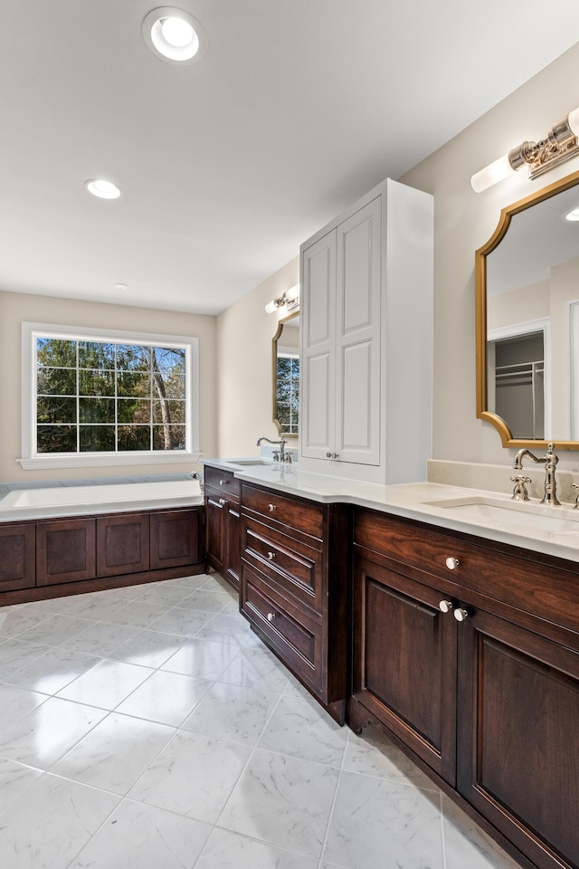 full bath with marble finish floor, double vanity, a sink, and recessed lighting