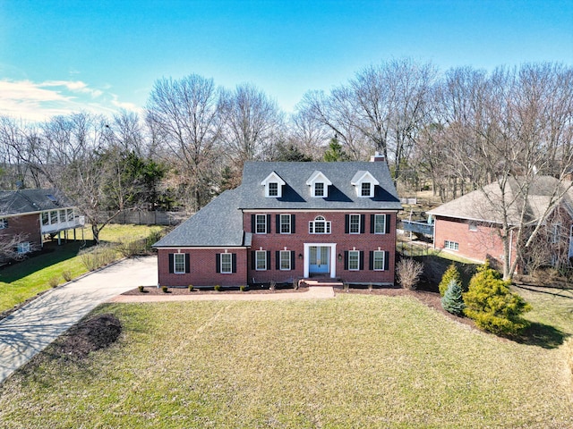 view of front of house featuring driveway, brick siding, and a front yard