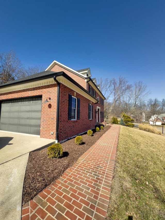 view of side of home with concrete driveway, brick siding, and an attached garage