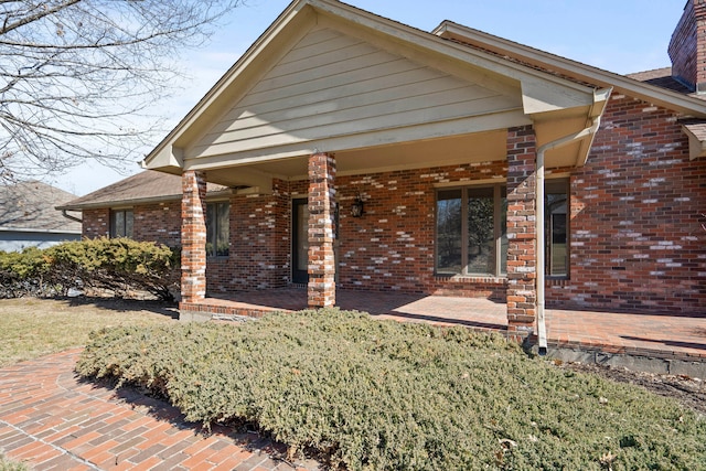 exterior space with a porch and brick siding