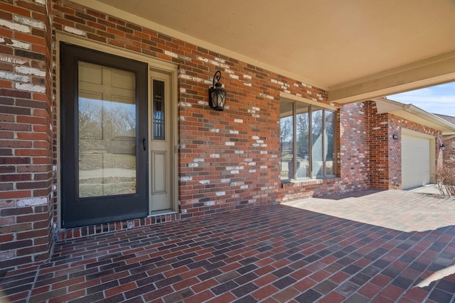 entrance to property with an attached garage and brick siding