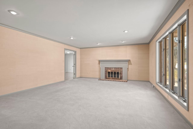 unfurnished living room with crown molding, recessed lighting, carpet, and a brick fireplace