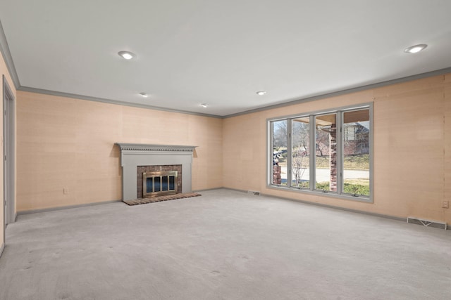 unfurnished living room with ornamental molding, carpet, visible vents, and a brick fireplace