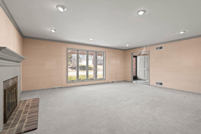 unfurnished living room with ornamental molding, a tile fireplace, visible vents, and carpet