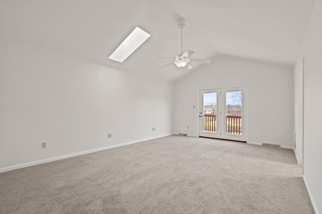 spare room with visible vents, a ceiling fan, baseboards, lofted ceiling with skylight, and carpet