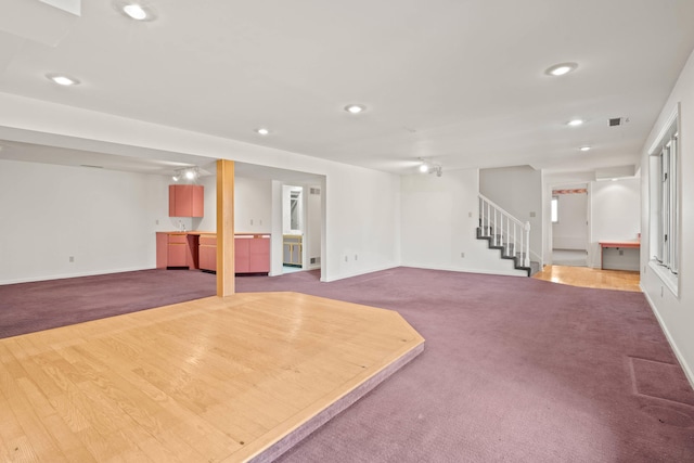 finished below grade area with carpet, baseboards, recessed lighting, and stairs