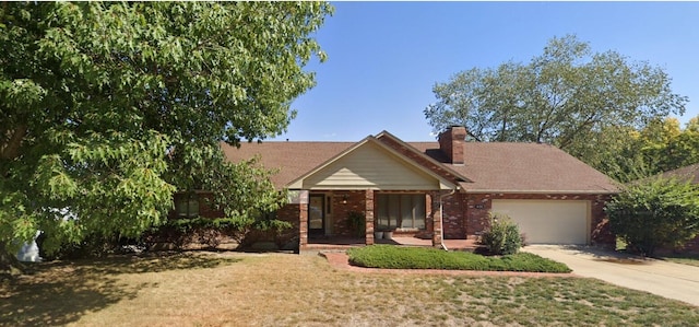 view of front facade with brick siding, concrete driveway, a chimney, an attached garage, and a front yard