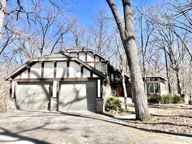 view of side of home featuring driveway, stucco siding, an attached garage, and brick siding