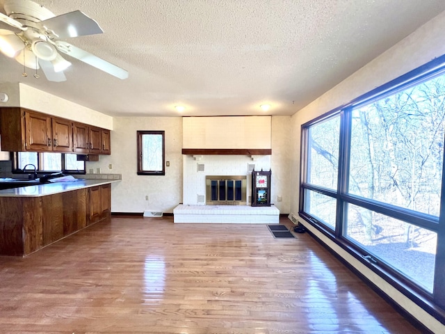 kitchen with a textured ceiling, a fireplace, a sink, wood finished floors, and open floor plan