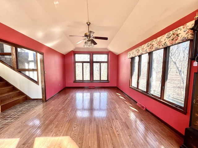 unfurnished living room with lofted ceiling, baseboards, stairway, and hardwood / wood-style floors