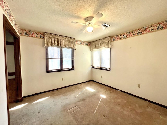 carpeted empty room with a textured ceiling, a ceiling fan, and baseboards