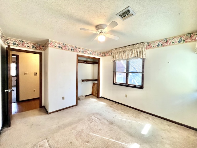 unfurnished bedroom with a textured ceiling, a ceiling fan, visible vents, baseboards, and a closet