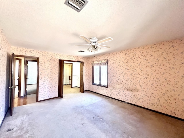 empty room featuring visible vents, ceiling fan, baseboards, and wallpapered walls