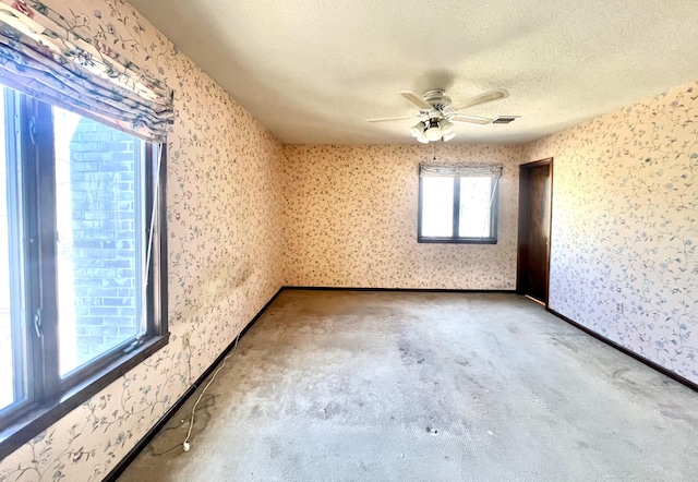 empty room with a textured ceiling, carpet, and wallpapered walls