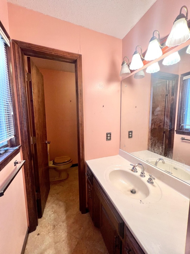 bathroom featuring a textured ceiling, toilet, and vanity