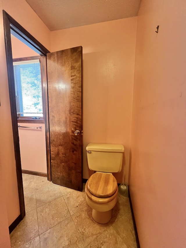 bathroom featuring tile patterned flooring, baseboards, and toilet