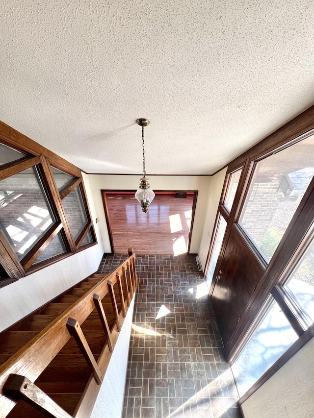 hallway with a textured ceiling and brick patterned floor