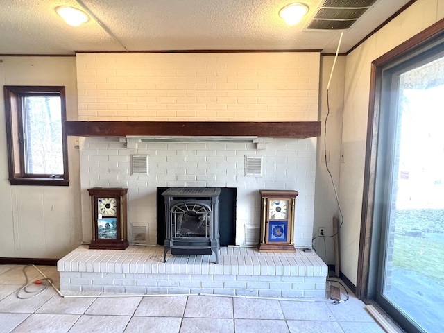 interior details featuring a wood stove, visible vents, crown molding, and a textured ceiling