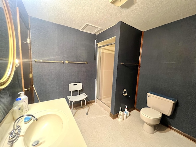 bathroom featuring toilet, a shower stall, baseboards, and a textured ceiling