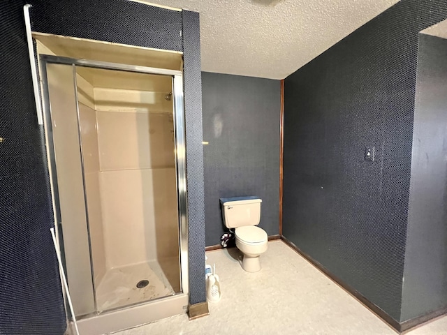 full bathroom featuring a textured wall, a shower stall, toilet, and a textured ceiling