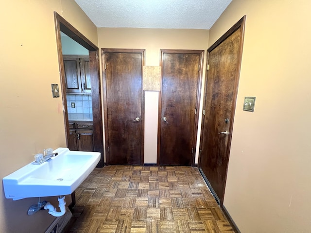 hall with a textured ceiling and a sink