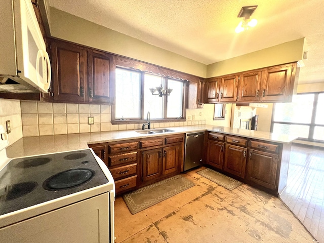 kitchen with light countertops, backsplash, a sink, white appliances, and a peninsula