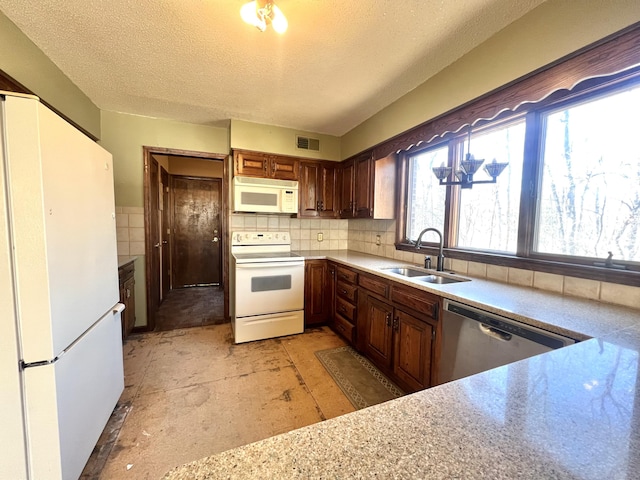 kitchen featuring white appliances, visible vents, light countertops, a textured ceiling, and a sink