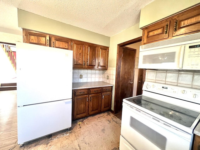 kitchen featuring a textured ceiling, light countertops, white appliances, and tasteful backsplash