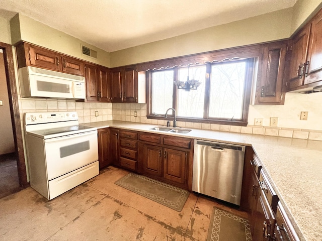 kitchen with tasteful backsplash, light countertops, visible vents, a sink, and white appliances