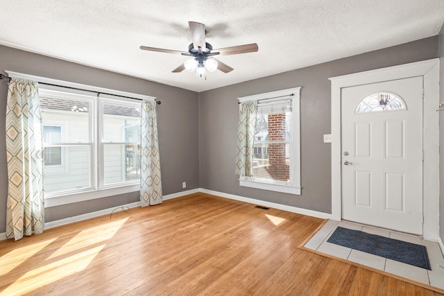 entryway featuring baseboards, visible vents, a textured ceiling, and light wood finished floors