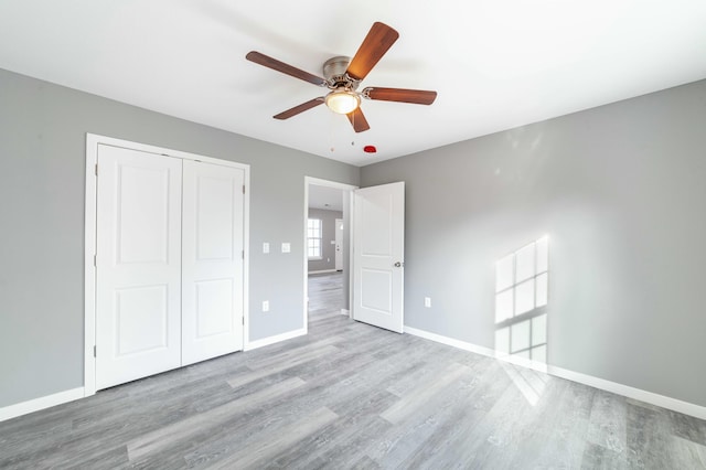 unfurnished bedroom with ceiling fan, a closet, wood finished floors, and baseboards