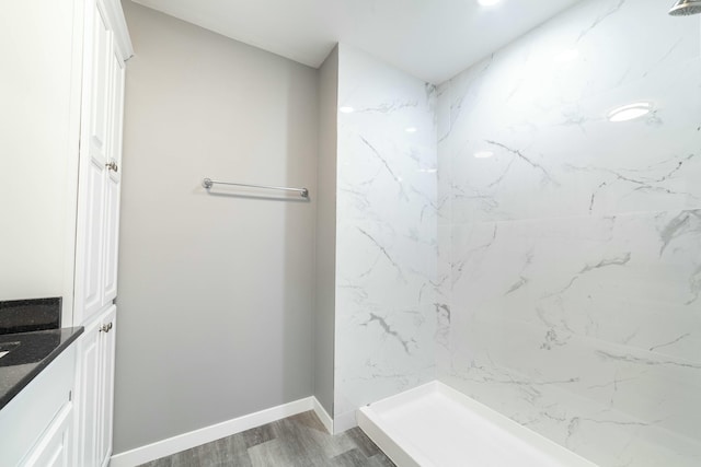 bathroom featuring a stall shower, baseboards, wood finished floors, and vanity