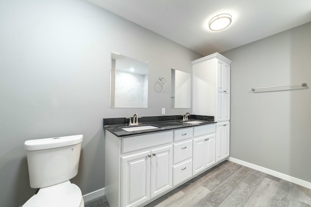 bathroom with toilet, baseboards, a sink, and wood finished floors