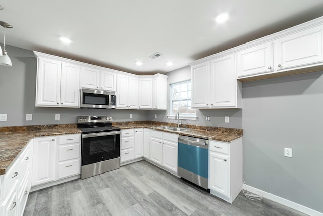 kitchen with stainless steel appliances, a sink, visible vents, and white cabinets