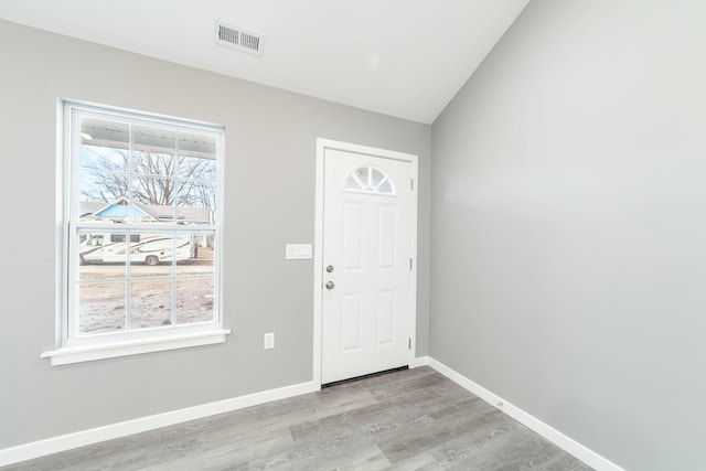 foyer with light wood-type flooring, visible vents, baseboards, and vaulted ceiling