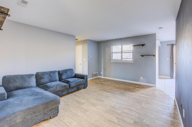 living room featuring light wood-style floors, baseboards, and visible vents