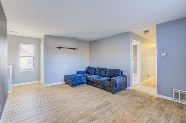 living area featuring visible vents, light wood-style flooring, and baseboards