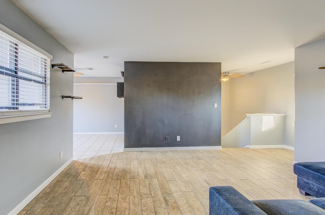 interior space featuring baseboards, a ceiling fan, and wood finished floors