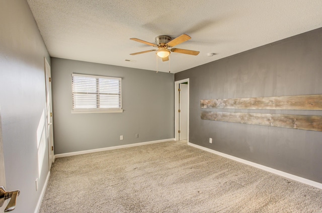 spare room with baseboards, carpet, a ceiling fan, and a textured ceiling