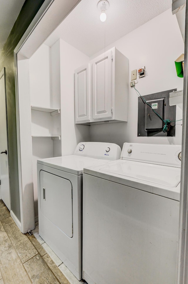 washroom with light wood-type flooring, cabinet space, a textured ceiling, and separate washer and dryer