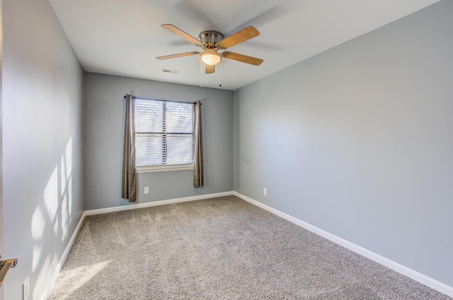 spare room with carpet, visible vents, baseboards, and ceiling fan