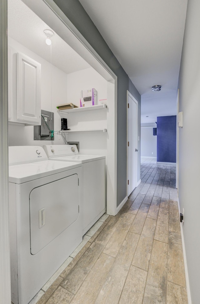 laundry room with light wood-type flooring, cabinet space, independent washer and dryer, and baseboards