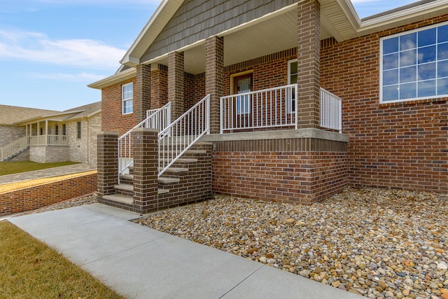 property entrance with covered porch and brick siding